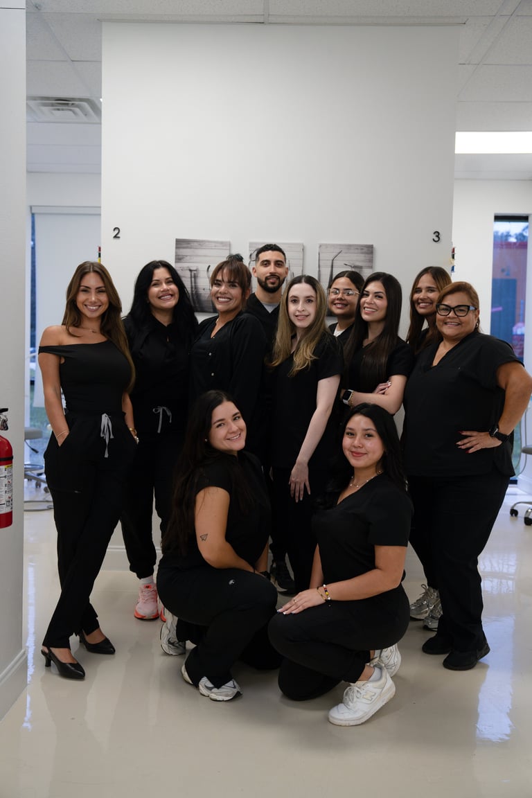 Group of 11 people in black professional attire posing together in a modern office or clinical setting.